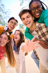 Vertical multiracial group of teenagers taking a selfie looking front camera laughing and having...