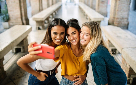 Young happy group of multiracial best women friends taking selfie portrait on cellphone app during summer vacation in Italy. Youth, travel and female friendship concept