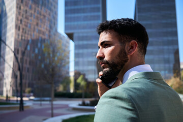 Young handsome Caucasian business man walking talking on phone serious expression. Male...