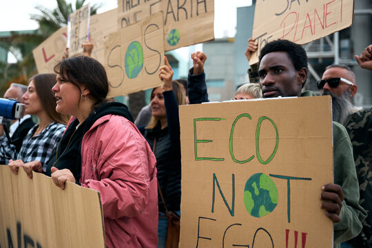 Serious African man holding a banner in a demonstration. Group of people at manifestation on climate change and global warming pollution and factories, environmentalists involved in the fight against 