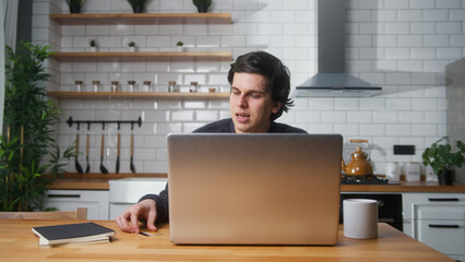 Man sitting in the modern kitchen entering credit card number on laptop for makes secure easy...
