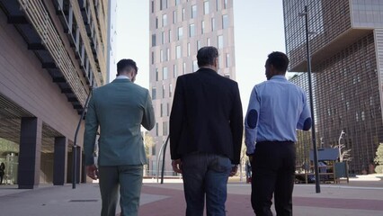 Back view three business men walking for city outside office in financial center. Place of work, planning and discussing new project, professionals job team. Enterprising people have chat on street.