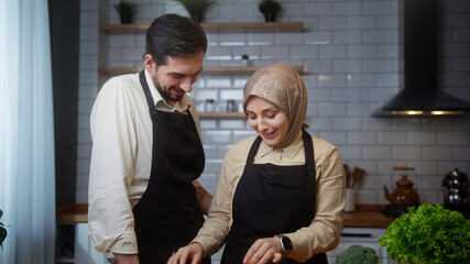 Smiling couple enjoy conversation in the modern kitchen and prepare healthy vegetarian food preparation together	
