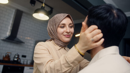 Overjoy young married couple standing at home, the woman caresses her husband cheek, laughing together. Wife shows her husband affection, married couple is enjoying time together	
