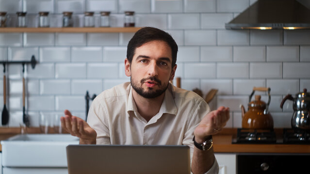 A businessman talking to the camera while sitting in the kitchen