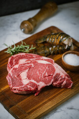 fresh ribeye steak and lobster tail on white marble background