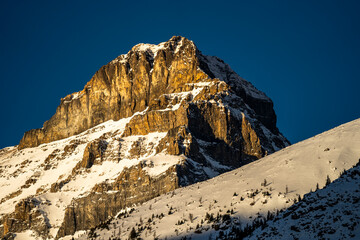 sun lighting up rocky cliff slightly covered in snow