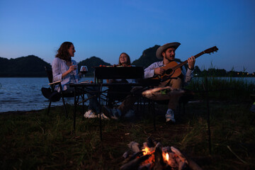 happy family camping party with BBQ, and grilled fish and wine by the  riverside, at evenning