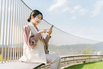 屋上でスマートフォンを使って電話する女性・ビジネスウーマン
