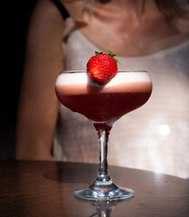 Glass of alcoholic margarita cocktail near blurred female model, close up.