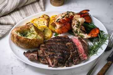 surf and turf, ribeye steak and lobster tail on white marble background