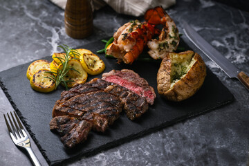 surf and turf, ribeye steak and lobster tail on black marble background
