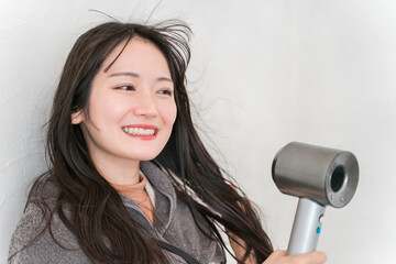 ヘアドライヤーでヘアブロー・髪の毛を乾かす女性（ヘアケア）
 - obrazy, fototapety, plakaty