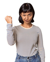 Young Hispanic woman with short black hair in studio showing fist to camera, aggressive facial expression.