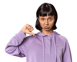 Young Hispanic woman with short black hair in studio showing a dislike gesture, thumbs down....