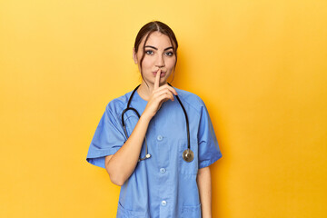 Young nurse in a yellow studio keeping a secret or asking for silence. - obrazy, fototapety, plakaty