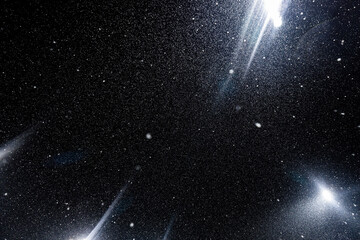 Floating dust particles. White dust texture on a black background with bright rays of light coming through the night sky. 