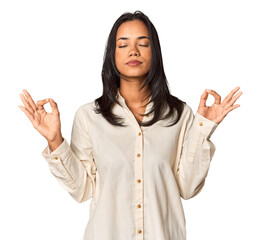 Young Filipina with long black hair in studio relaxes after hard working day, she is performing yoga.