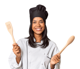 Young Filipina chef holding wooden spatulas in studio