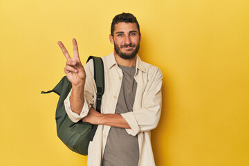 Young Hispanic man with travel backpack showing number two with fingers.