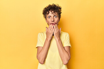 Mid-aged caucasian woman on vibrant yellow shocked, covering mouth with hands, anxious to discover...