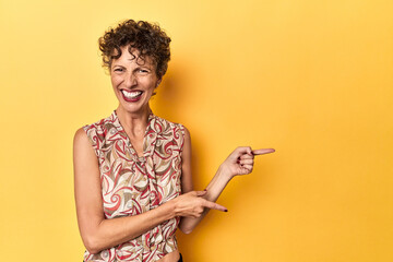 Mid-aged caucasian woman on vibrant yellow excited pointing with forefingers away.