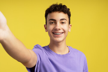 Smiling boy 15 years old influencer recording video having video call, wearing casual purple t shirt