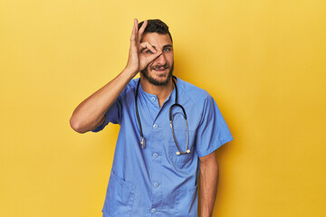 Young Hispanic male nurse Young Hispanic male nurse poses confidently excited keeping ok gesture on...