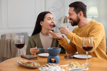 Affectionate couple enjoying chocolate fondue during romantic date at home
