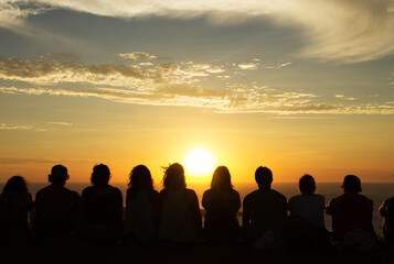 Group of people watching a sunset from a mountain 