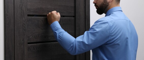 Collection agent knocking on wooden door, closeup