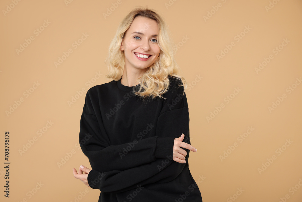 Wall mural Happy woman in stylish warm sweater on beige background