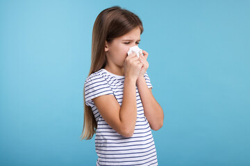 Sick girl with tissue coughing on light blue background
