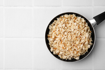 Fried ground meat in frying pan on white tiled table, top view. Space for text