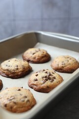 Baking pan with chocolate chip cookies on table, closeup