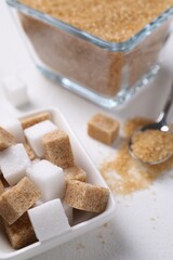 Different types of sugar in bowls on white table, closeup