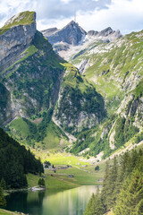 Picturesque view of an alpine lake in a green valley with a mountain peak in the background on a sunny day. Seealpsee, Säntis, Wasserauen, Appenzell, Switzerland.