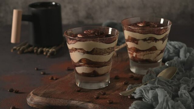 Delicious italian dessert tiramisu in a glasses on a dark slate, stone or concrete background.