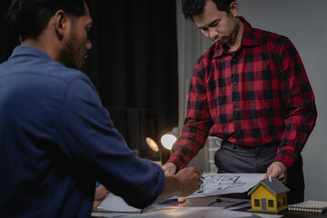 Meeting and presentation in office with architects, construction engineers and workers looking at building models and blueprint plans on tables, industrial and real estate concepts.