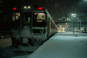 雪降る無人のホームに停車する夜行列車