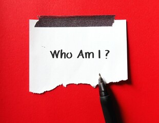 Stick note on red background with handwriting Who Am I? - concept of self-discovery - finding your...