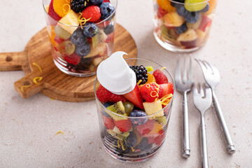 Fruit salad served in individual cups with banana, pineapples, berries, orange dressing and mint