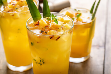Grilled pineapple cocktail or mocktail garnished with pineapple leaves