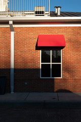 Four pane tined window with red awning on a brick building.