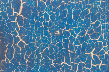 Cracked texture of blue paint on the wall.