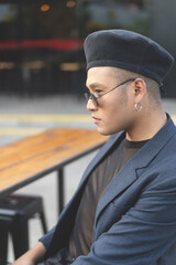 Latin gay male with makeup wearing fashion hat posing in the street