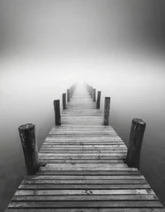 Foto op Plexiglas Minimalist artistic image of a wooden jetty disappearing into the fog in black and white. © Inge