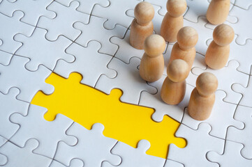 Missing jigsaw puzzle with wooden dolls. Representing hiring and copy space.