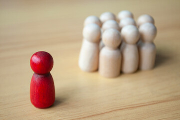 A single red wooden doll separated by other dolls. Representing either leadership or isolation