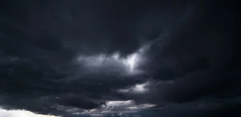 Fotobehang The dark sky with heavy clouds converging and a violent storm before the rain.Bad or moody weather sky and environment. carbon dioxide emissions, greenhouse effect, global warming, climate change. © death_rip